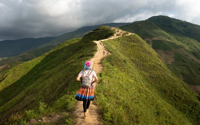 Person running along a path of a grass covered ridge